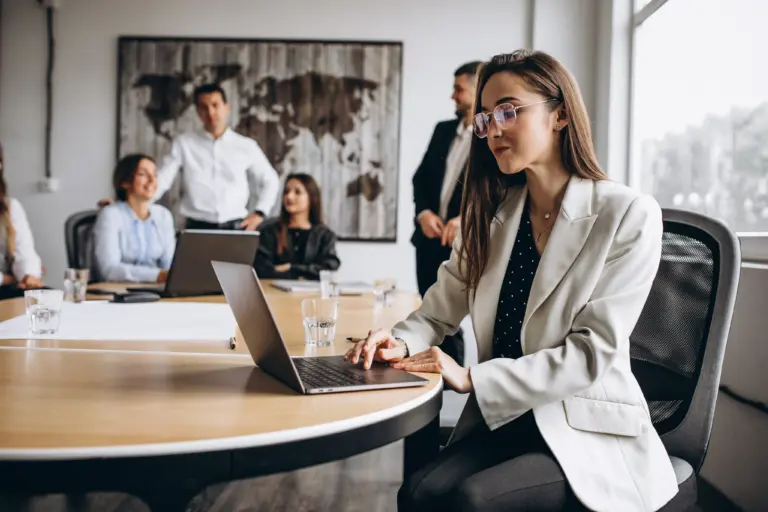 Professional working on a laptop during a team meeting